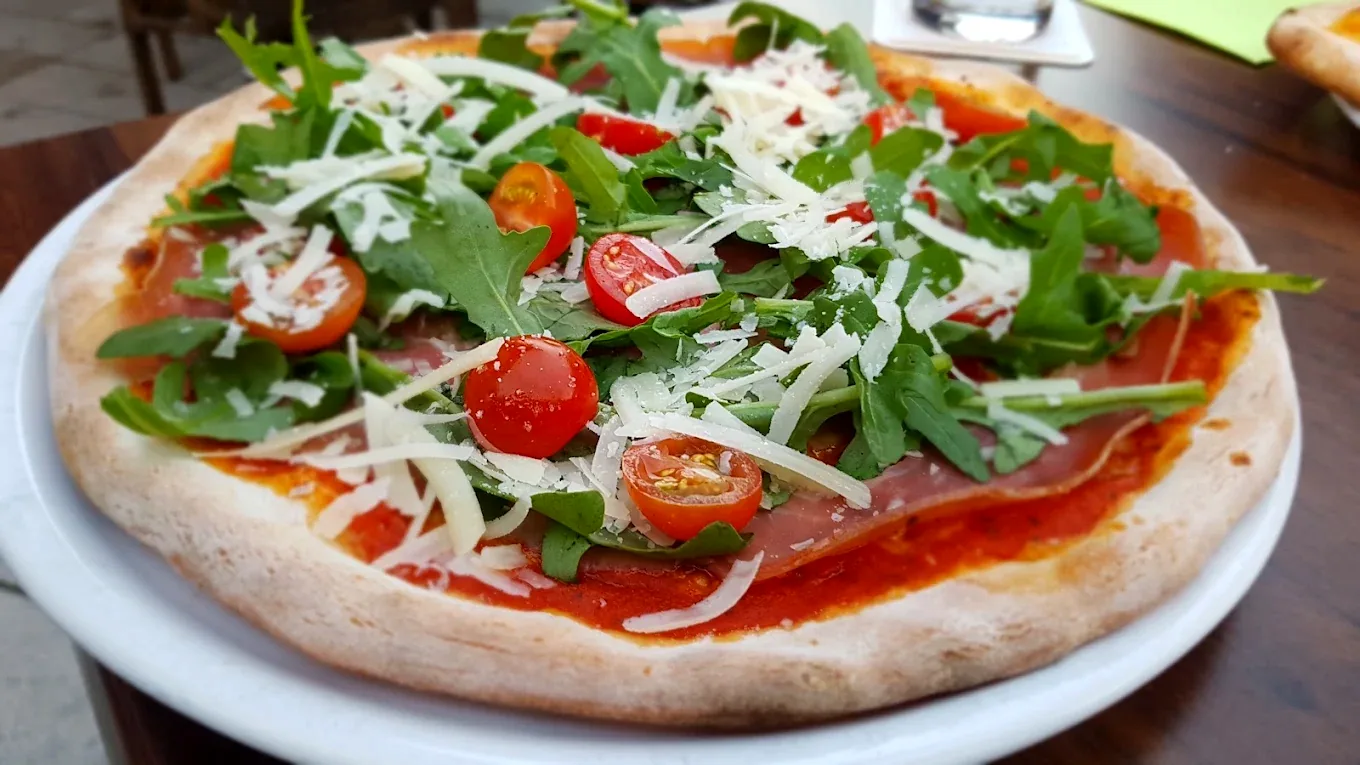 Pizza Italia mit Rucola, Parmaschinken, Cherrytomaten und Parmesan aus dem Steinofen – La Piazza Herdecke